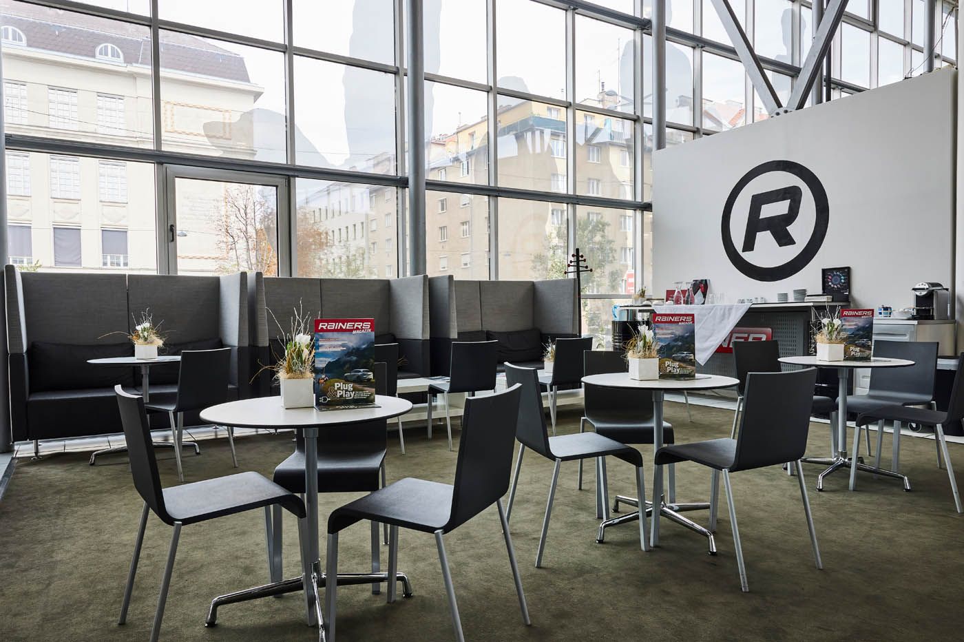 Moderner Lobby- oder Loungebereich mit kleinen runden Tischen, Stühlen, Sitznischen mit hoher Rückenlehne