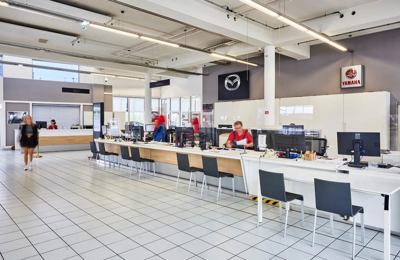 Der Servicebereich eines Mazda-Autohauses mit Reihen von Arbeitsplätzen, Computern und einem Kunden