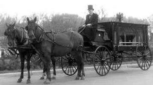 A black and white photo of a horse drawn carriage.