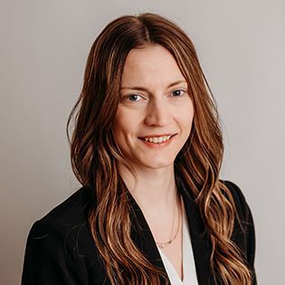 A woman wearing hoop earrings and a white shirt is smiling for the camera.