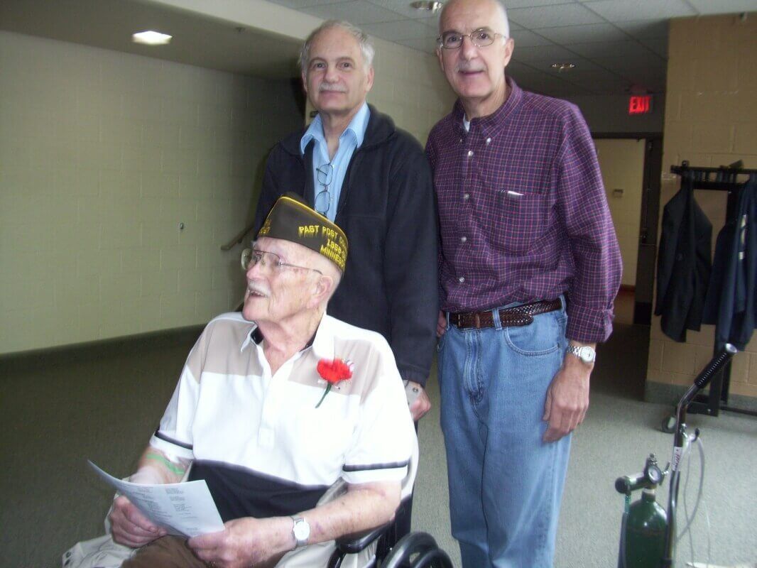 A man in a wheelchair is standing next to two other men