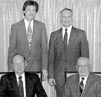 A black and white photo of four men in suits and ties