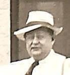 A black and white photo of a man wearing a hat and tie.