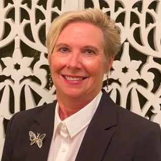 A woman wearing hoop earrings and a white shirt is smiling for the camera.