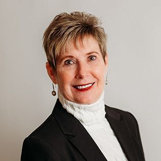 A woman wearing hoop earrings and a white shirt is smiling for the camera.