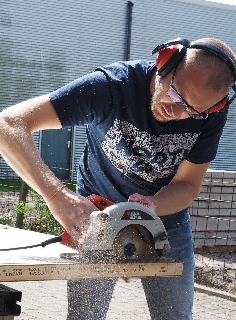 Carpenter wearing protective earphones sawing wood with an electric  rotary saw