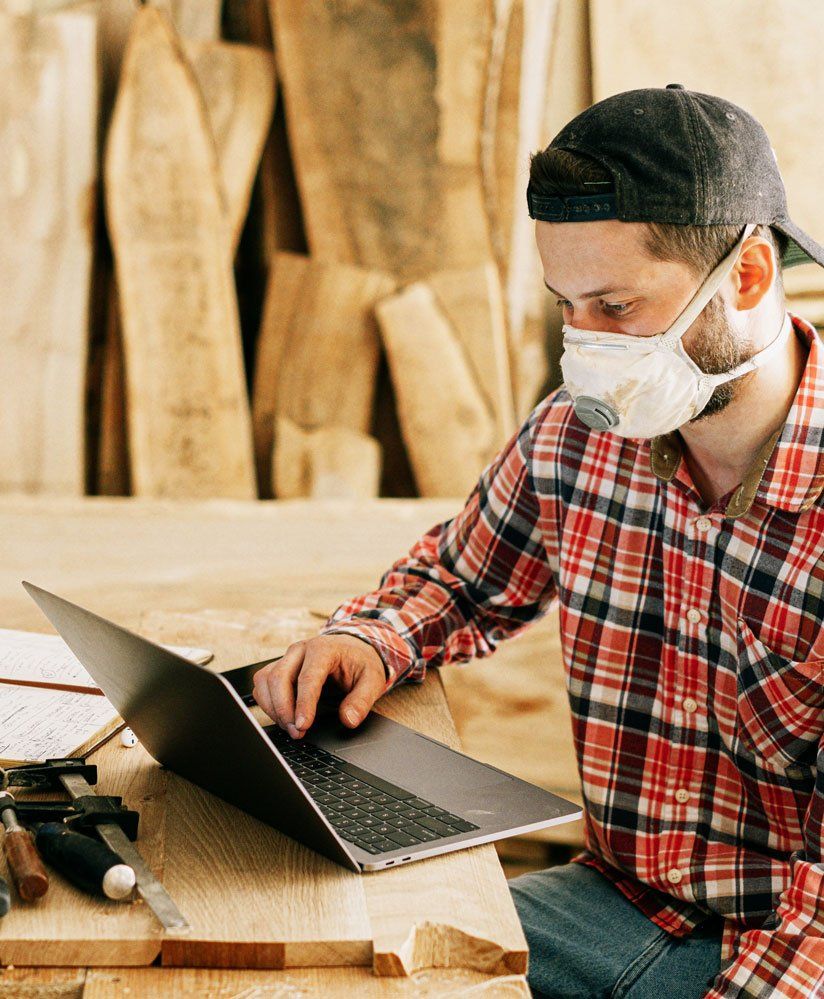 Designer in protective mask and checked shirt checking his laptop
