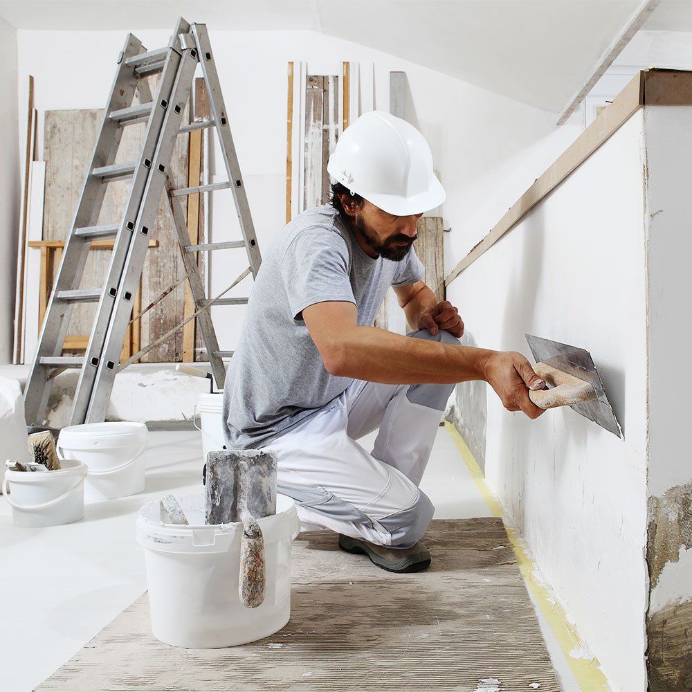 man with mortar board plastering a white wall
