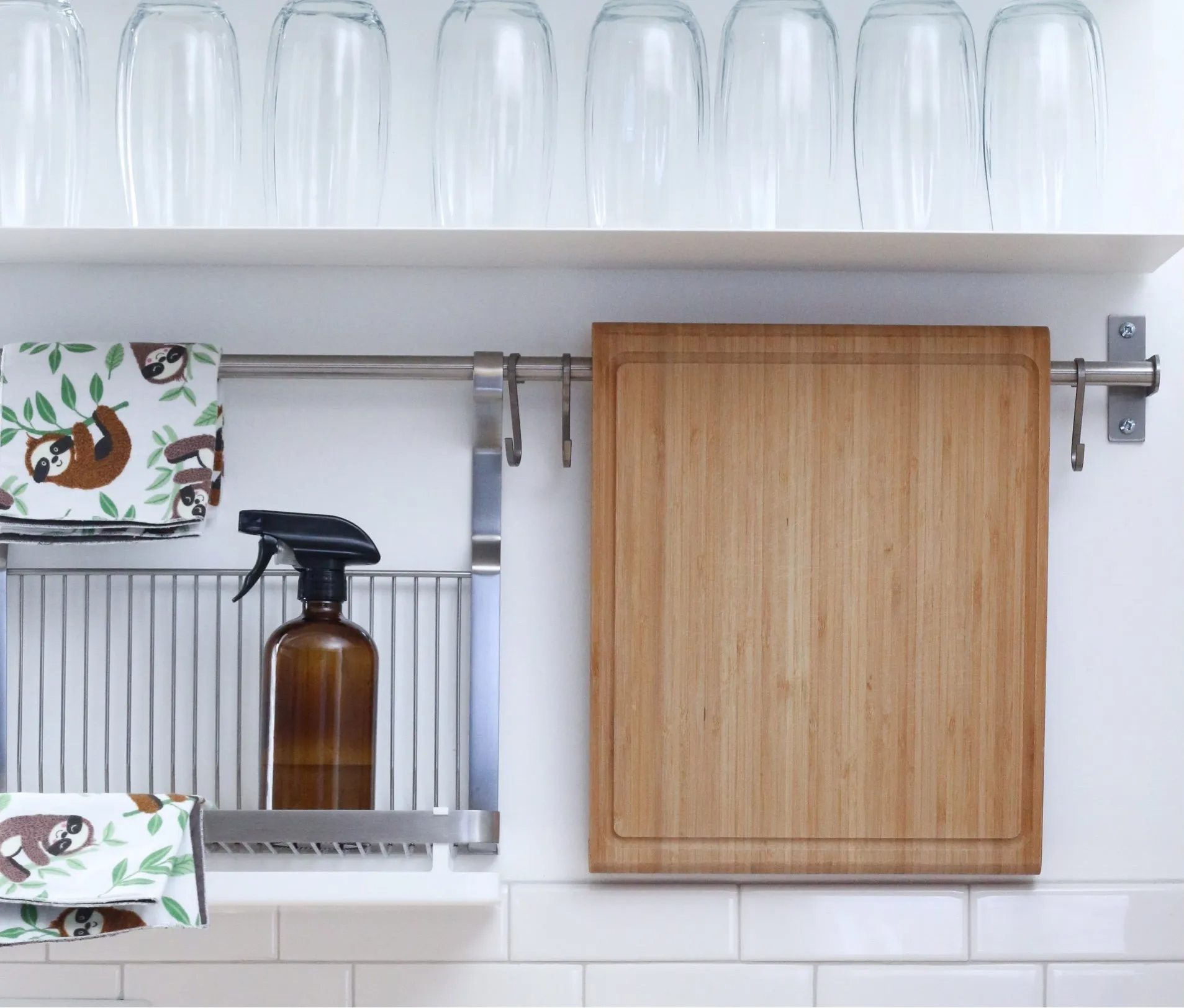 kitchen rail with glasses on top, pine chopping board and brown spray bottle