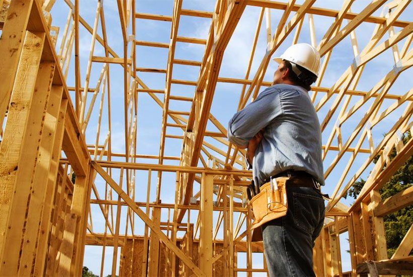Builder in white helmet checking wooden house foundations