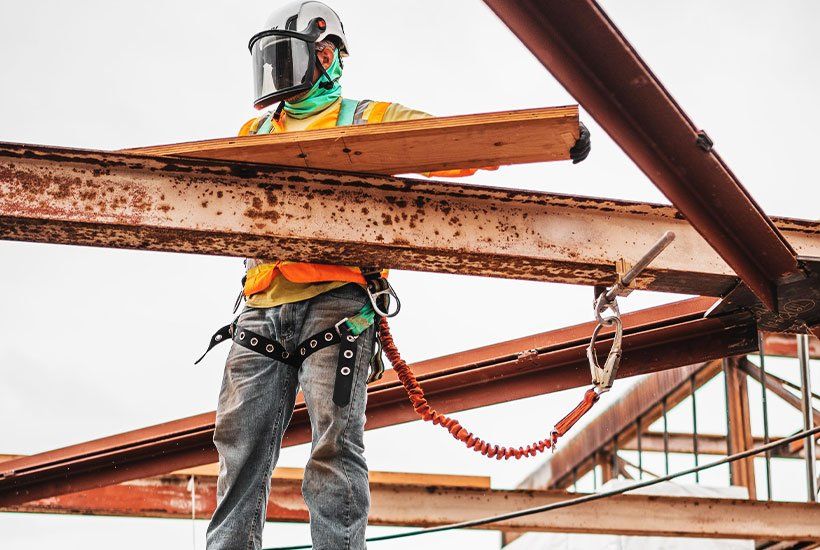 Builder in a protective helmet measuring a plank of wood