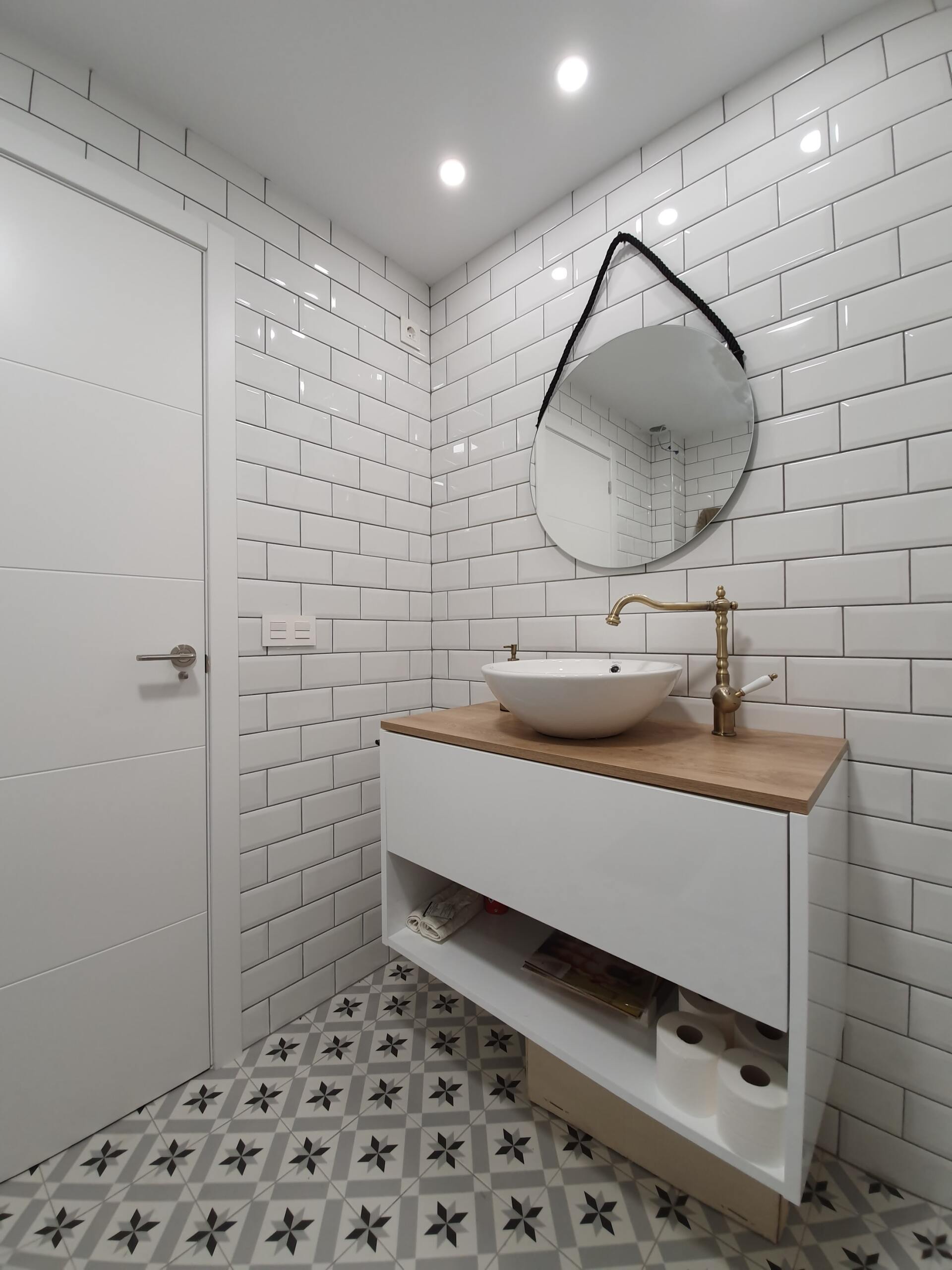 whitebathroom with contrasting floor tiles and round black mirror