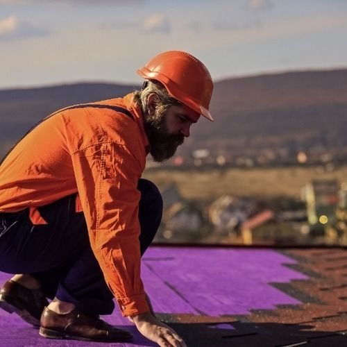 A man wearing an orange hard hat is working on a purple roof