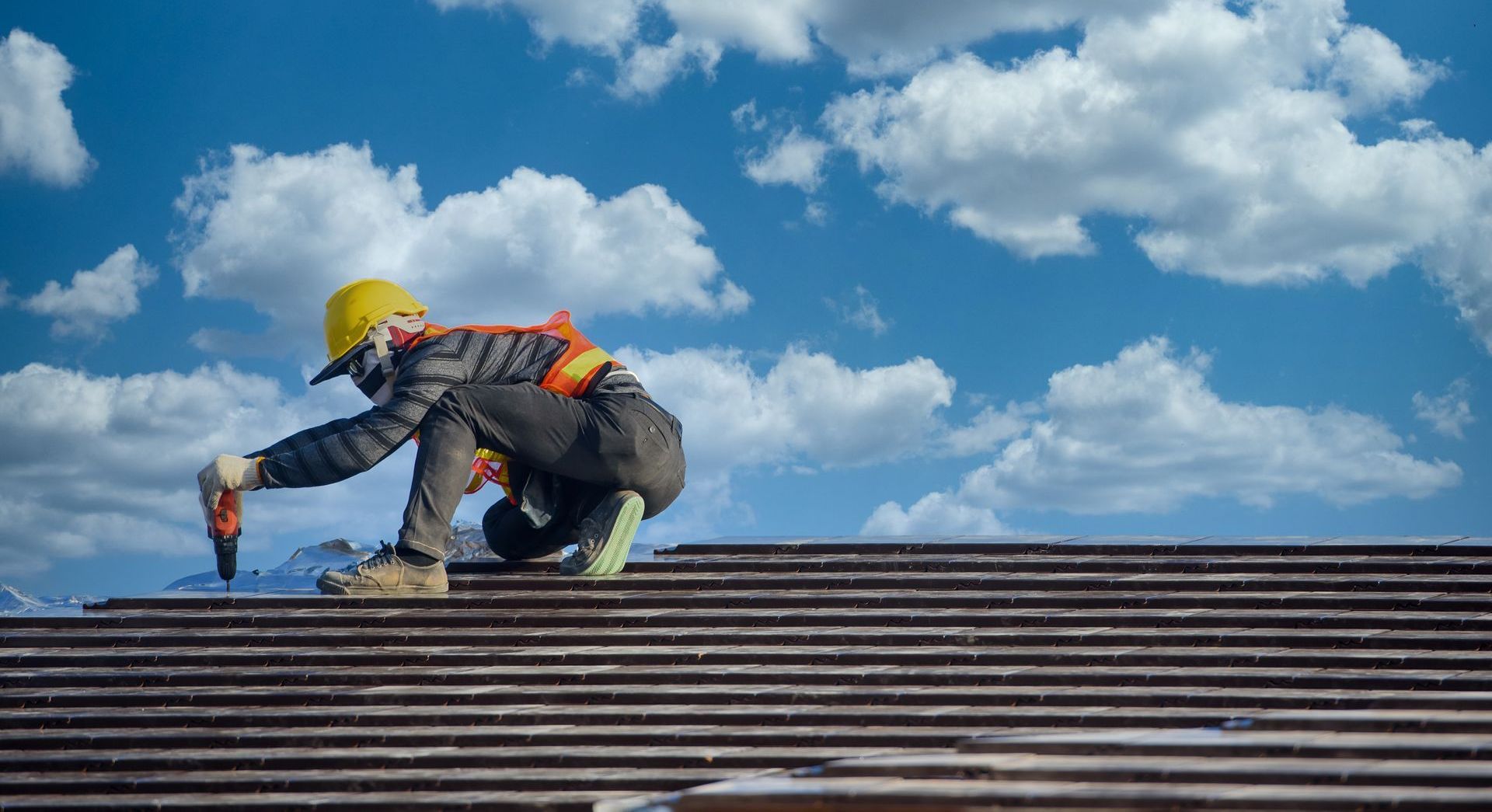 a man is working on a roof with a drill