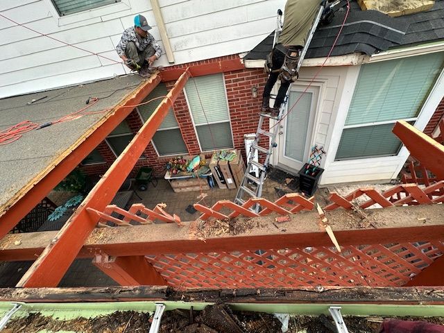 Two men are working on the roof of a house.