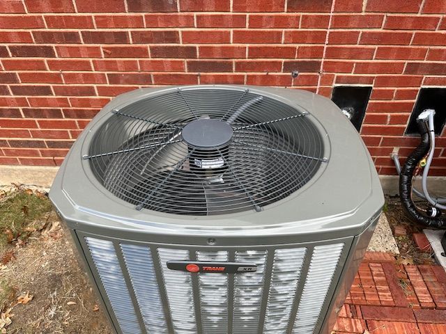 An air conditioner is sitting outside of a brick building.