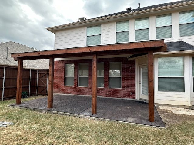 A large brick house with a wooden patio in front of it.