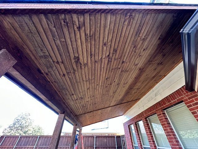 A wooden porch with a brick building in the background