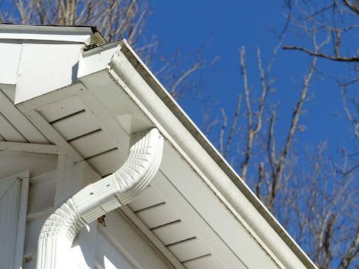 a white gutter on the side of a house with a blue sky in the background .