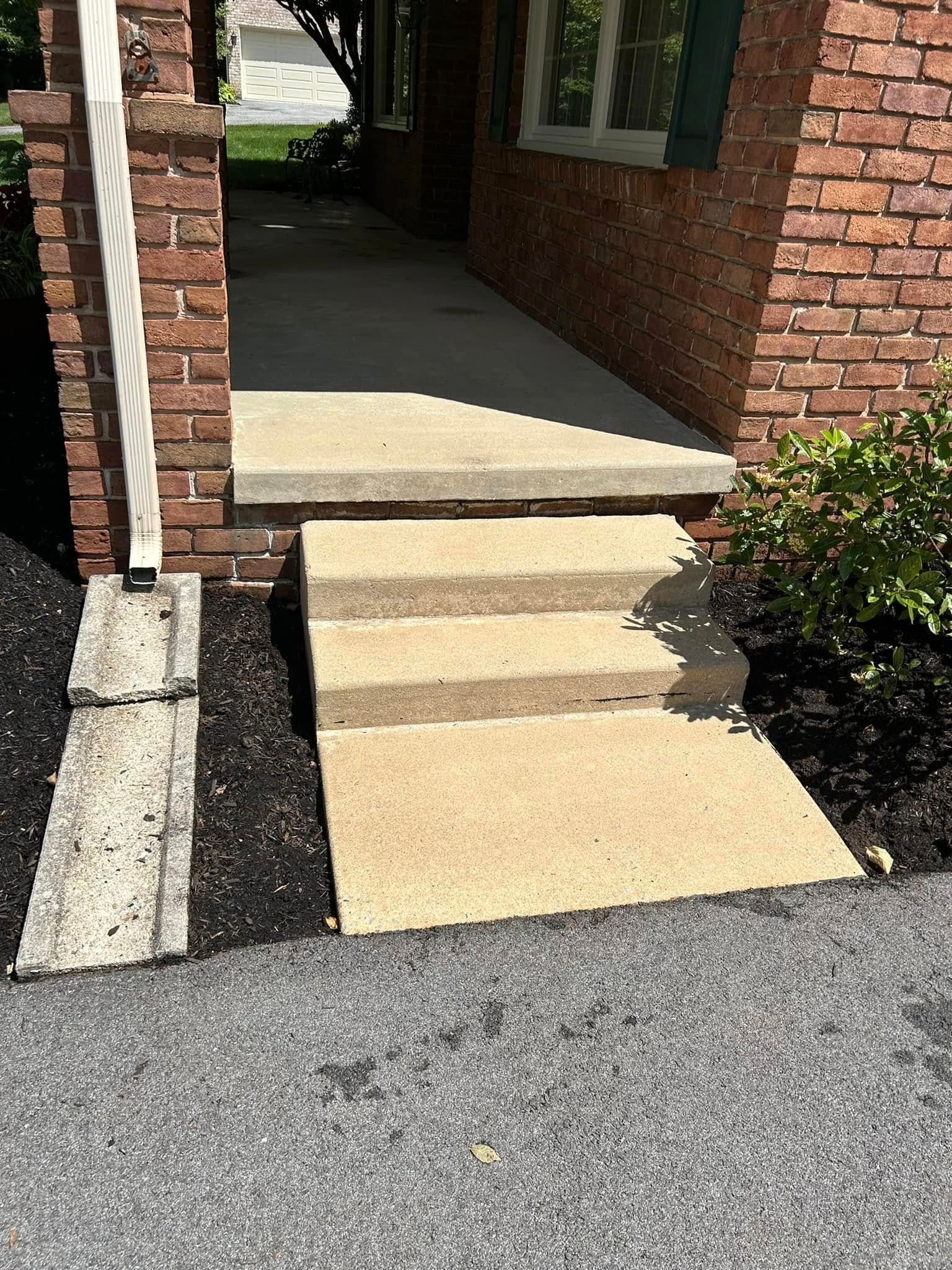 A set of concrete steps leading up to a brick house.