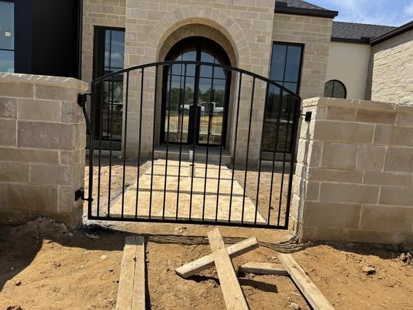 A wrought iron gate is sitting in front of a brick building.
