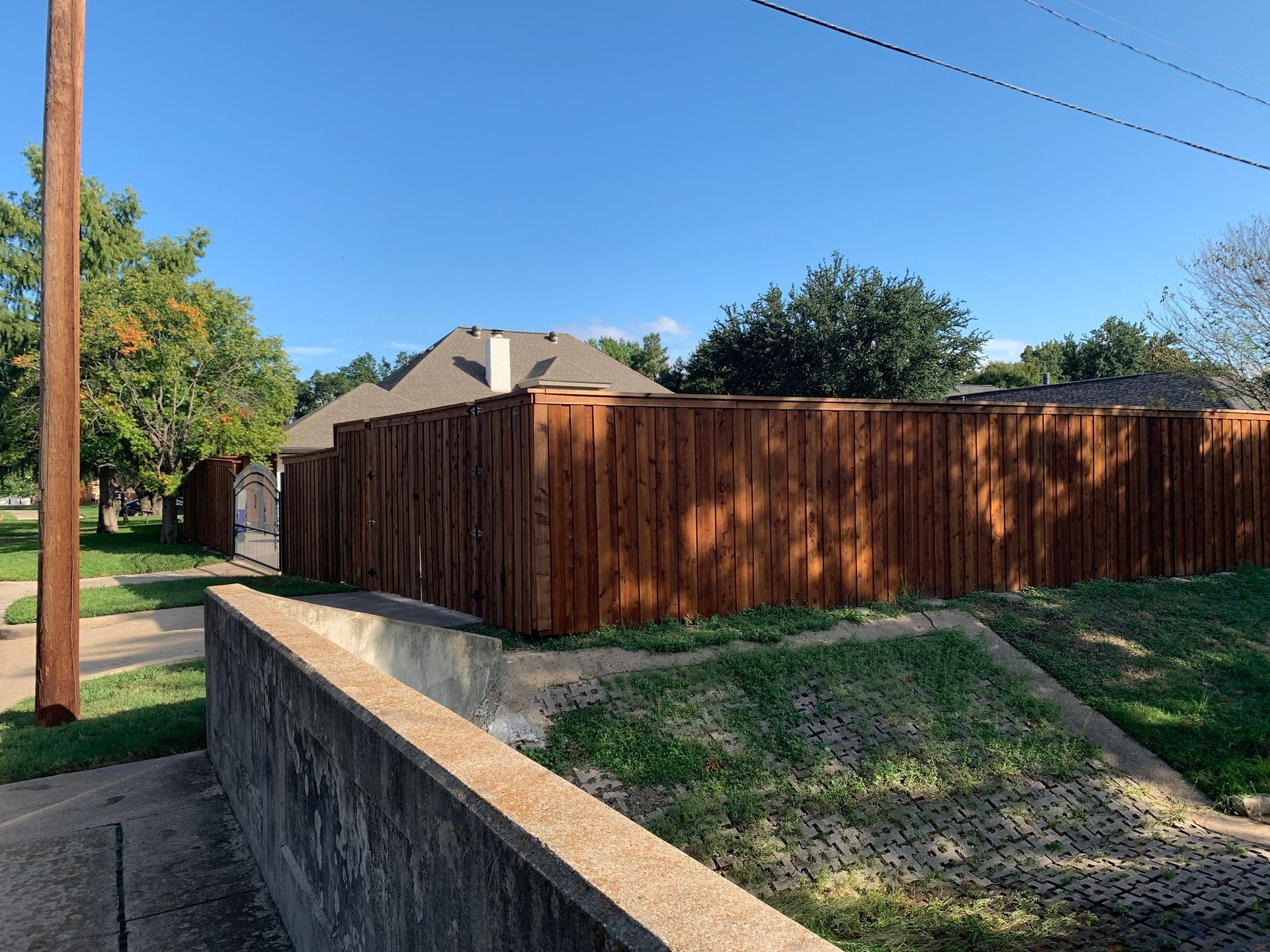 Wooden fence surrounding a house on a sunny day, brown and blue.
