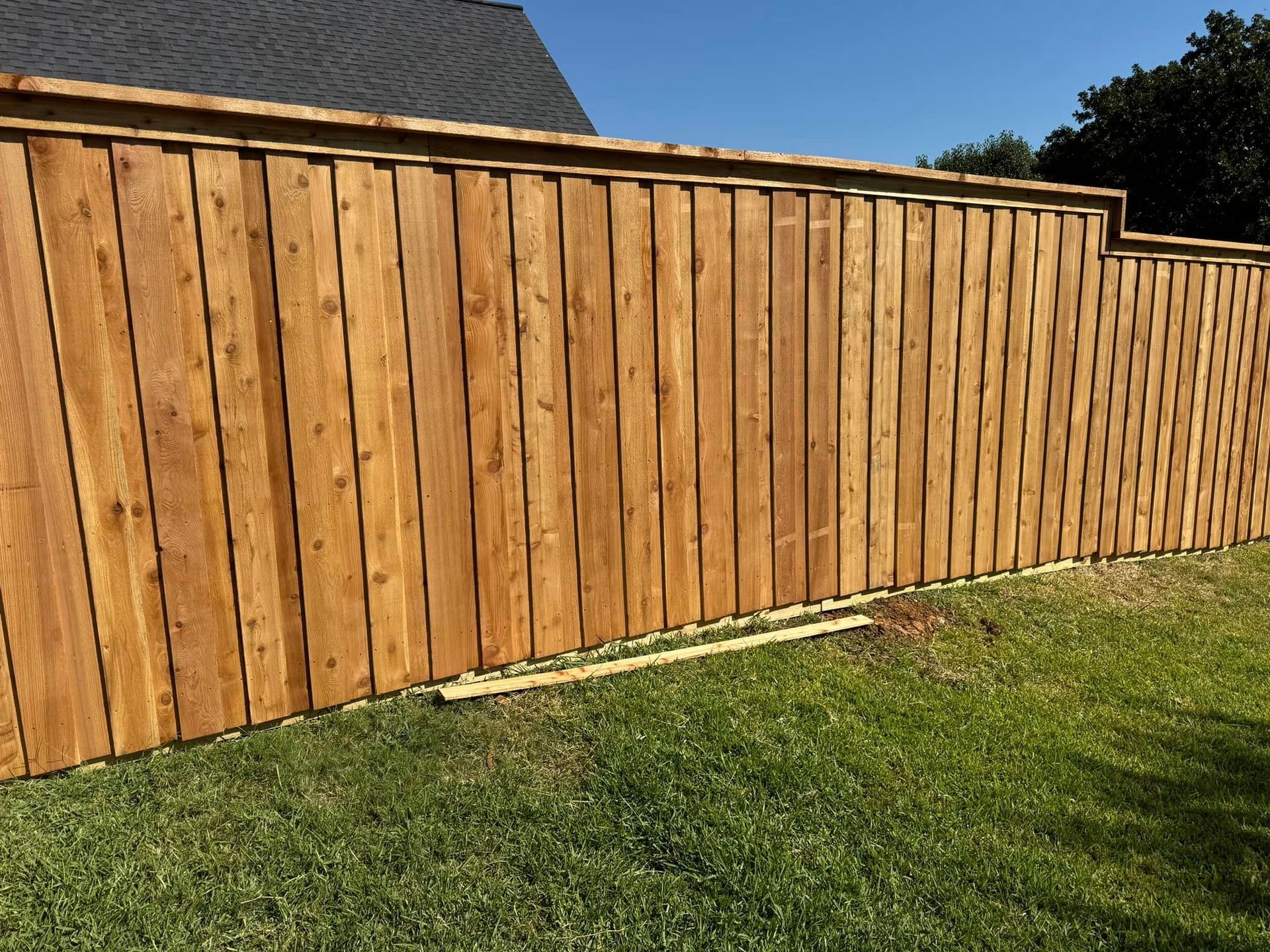 Wooden privacy fence on a green lawn against a blue sky.