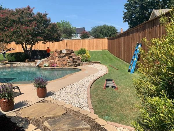 Backyard with a pool, wooden fence, and grass, with a ladder leaning against the fence.