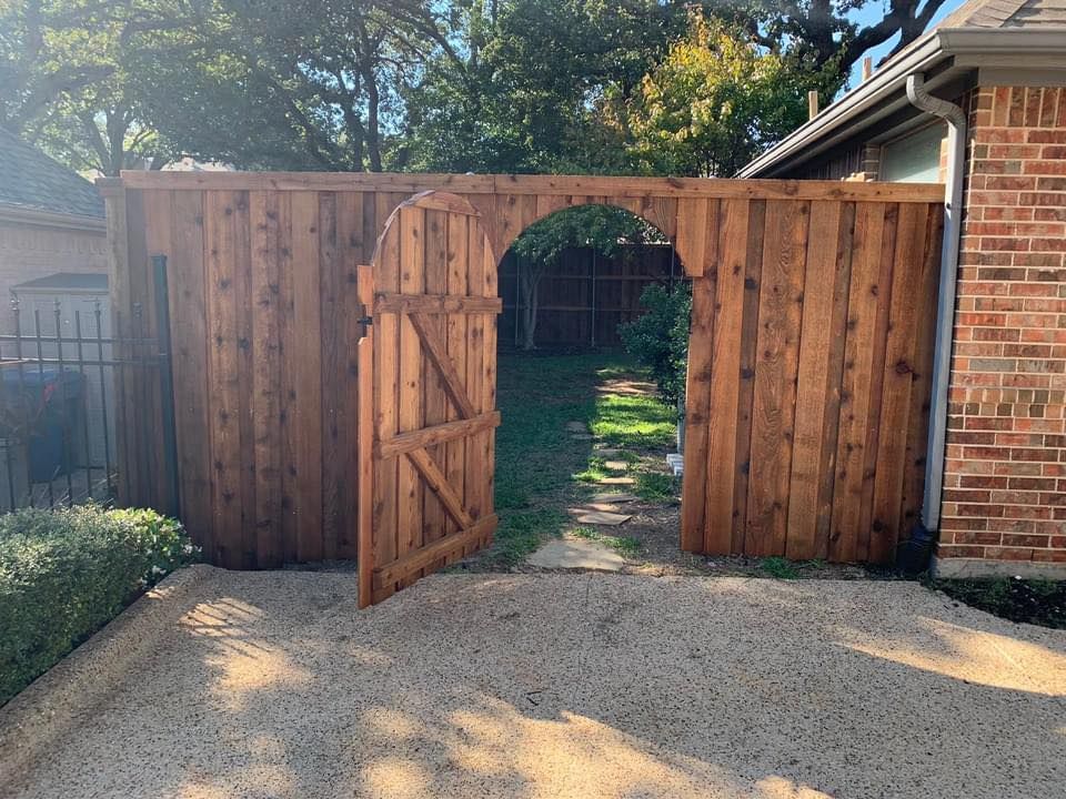 Wooden fence with arched gate, opening to a backyard. The gate is ajar.