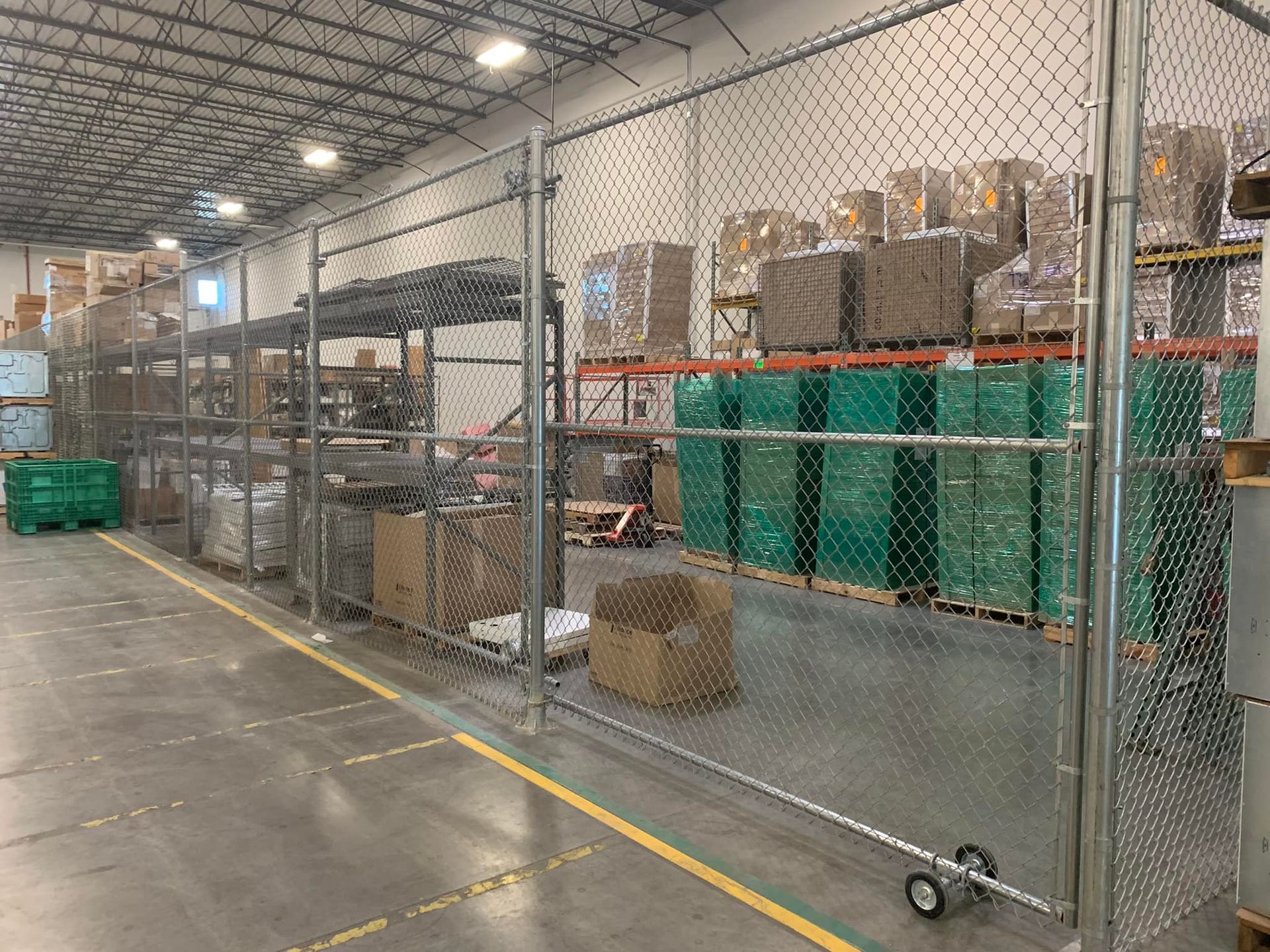 Warehouse interior with chain link fence separating storage. Boxes and bins line the shelves.