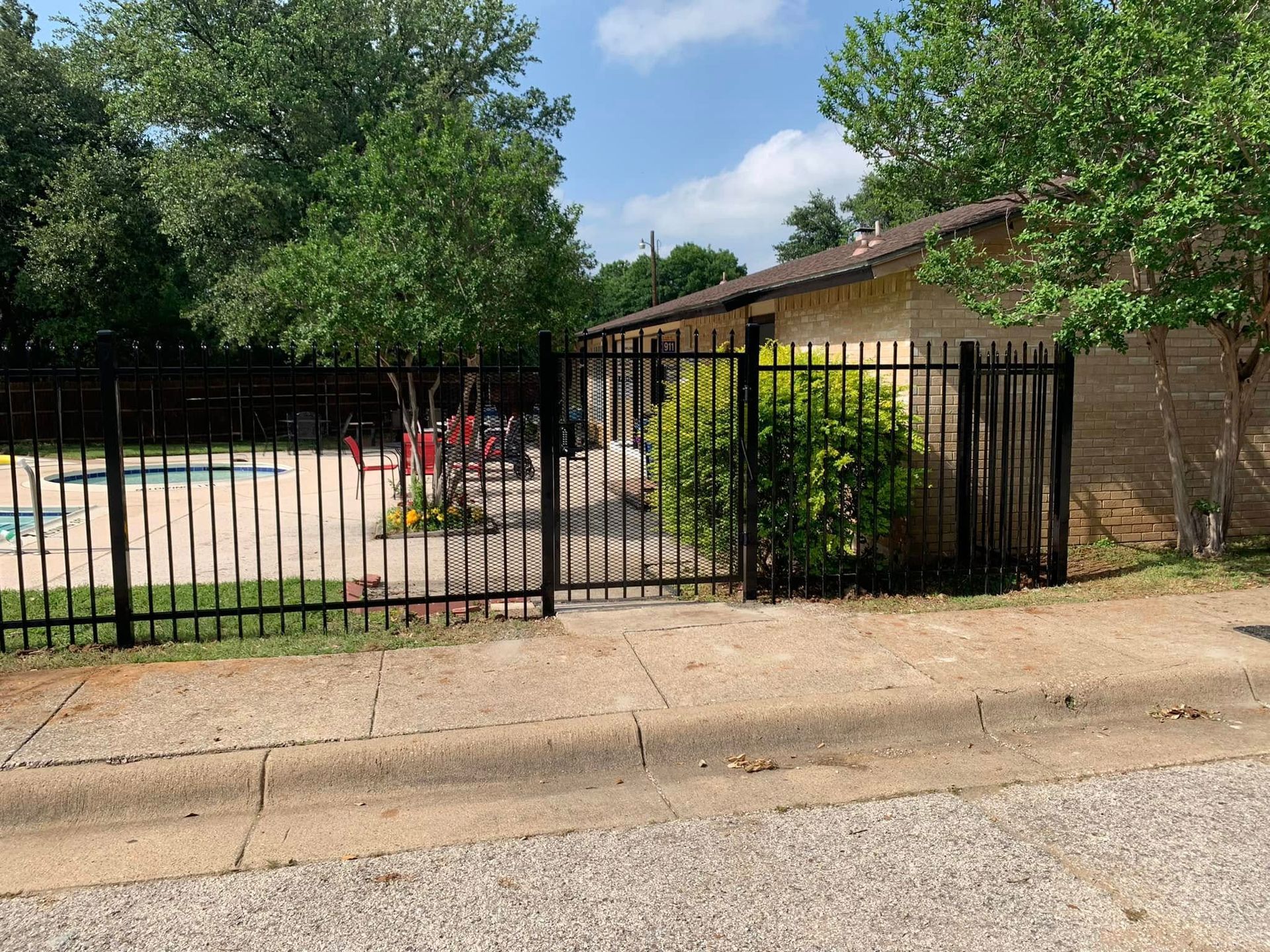 Black fence surrounding a pool area; building on right.