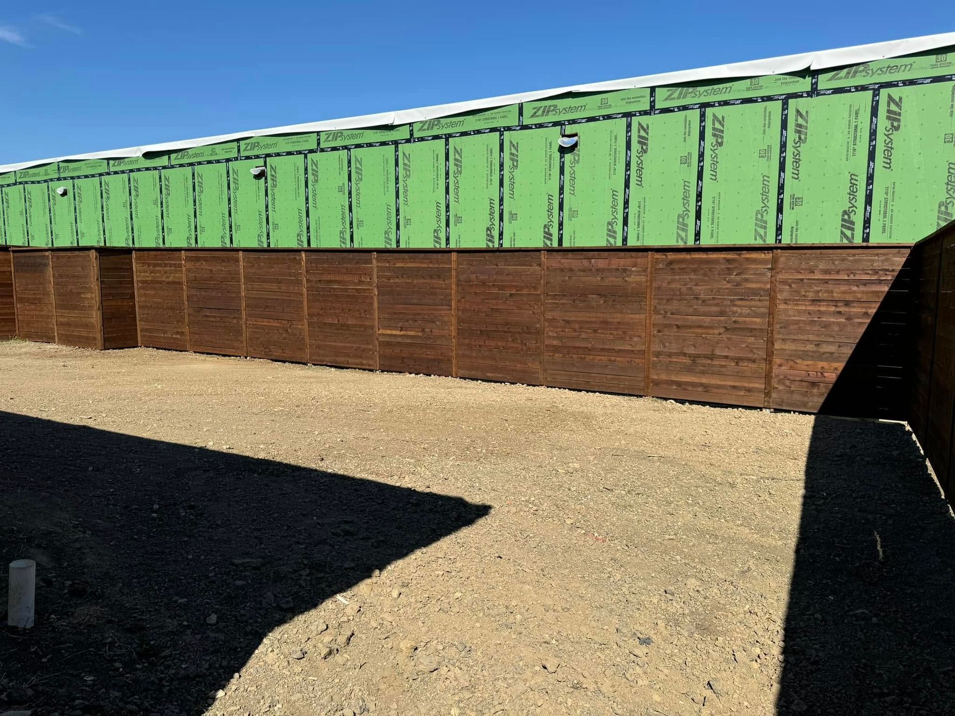 Brown wood paneling on building, gravel path, and green siding. Sunny day.