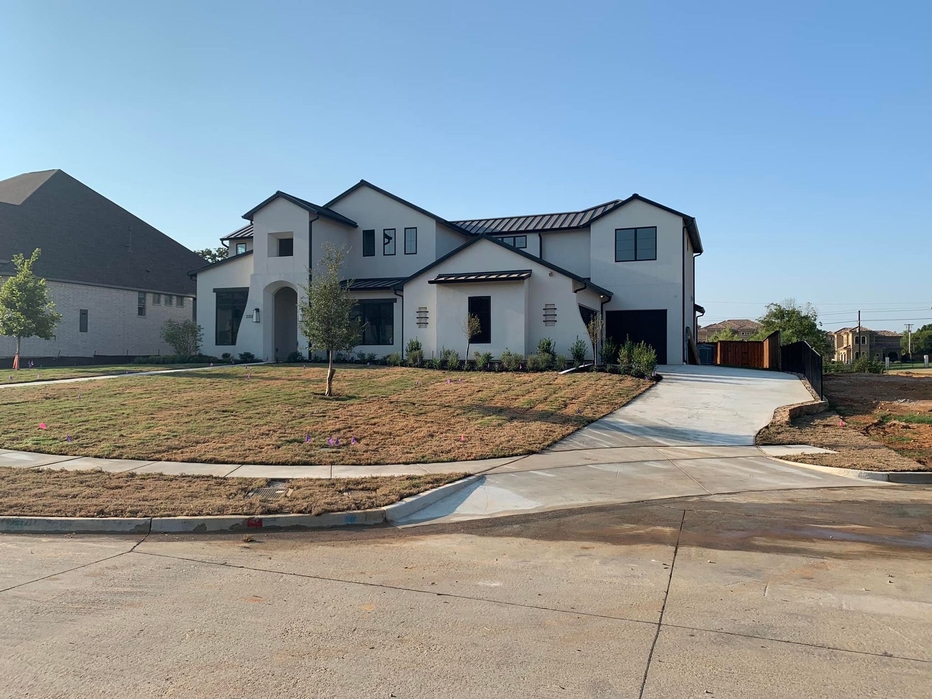 White house with black trim, driveway, and yard on a sunny day.