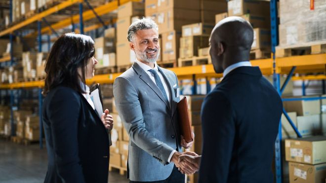 A group of business people are shaking hands in a warehouse.