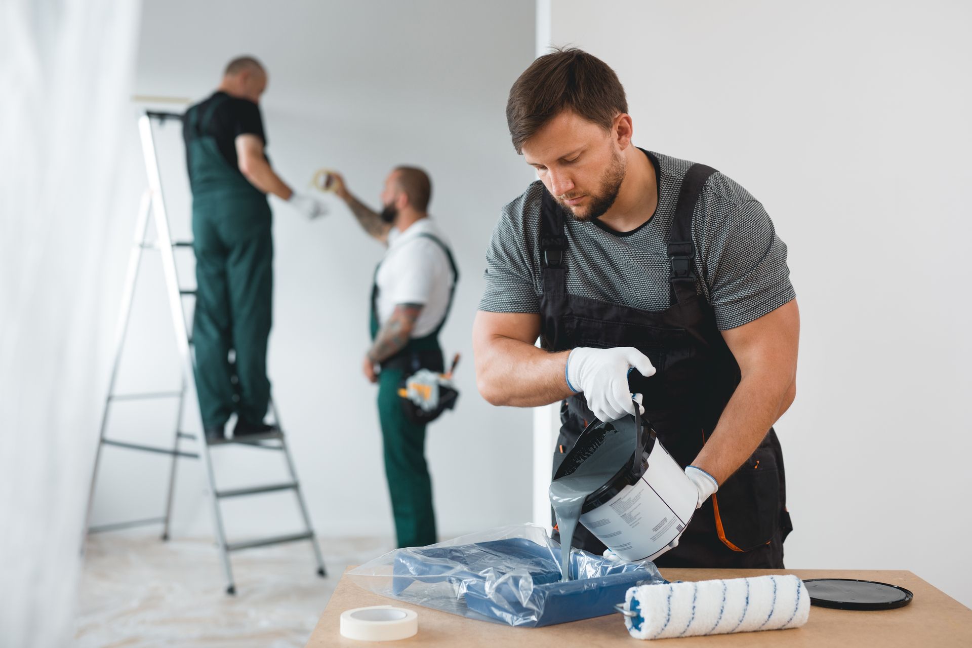 An efficient company crew is painting the white walls of a new build home interior.