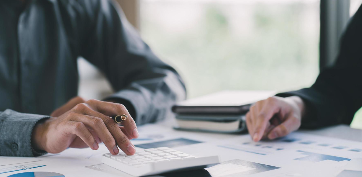 Hands using a calculator with financial documents on a table.