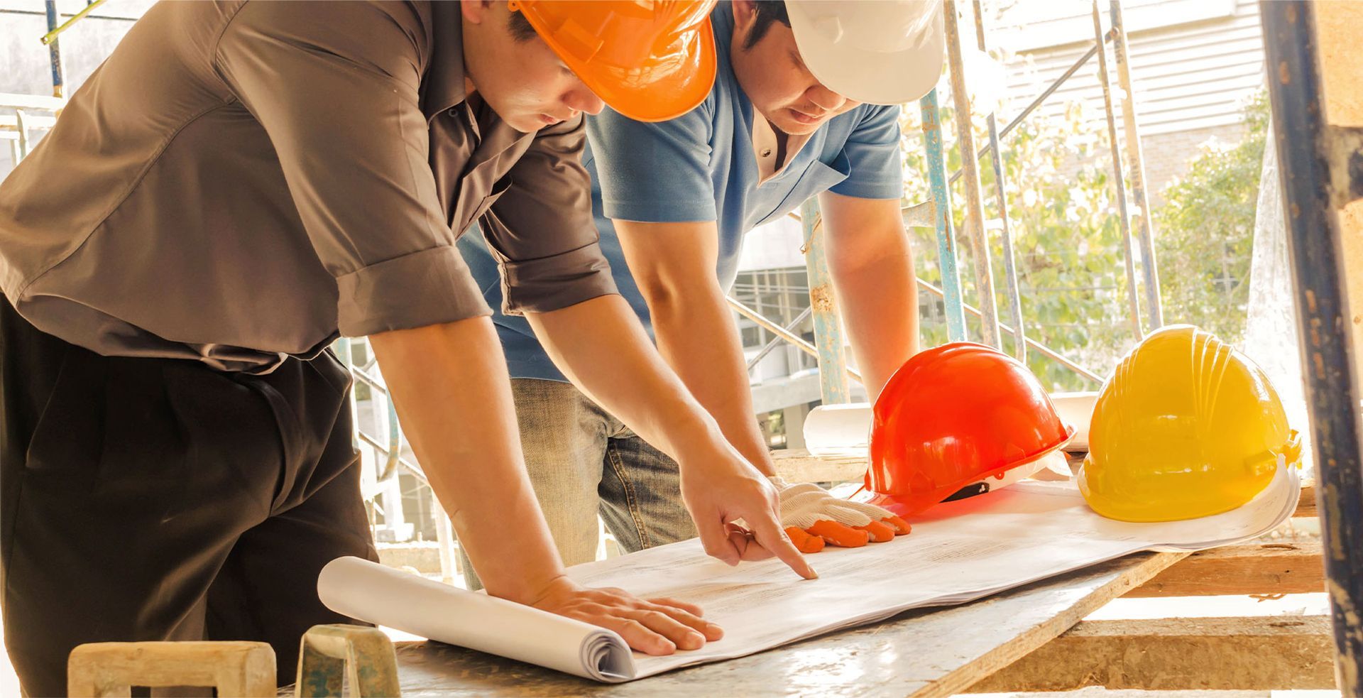 Two construction workers in hard hats reviewing blueprints.