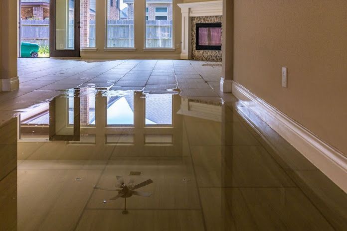 A flooded living room with a reflection of a window in the floor.