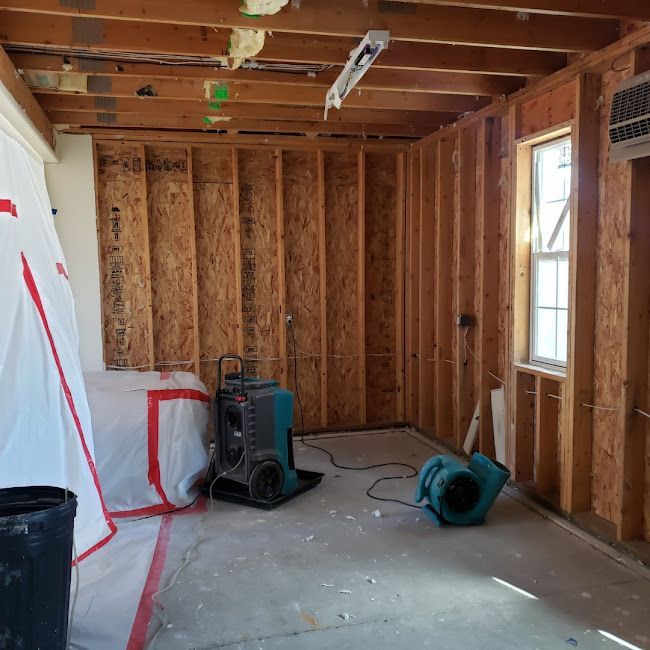 A room with a fan and a white tarp on the floor