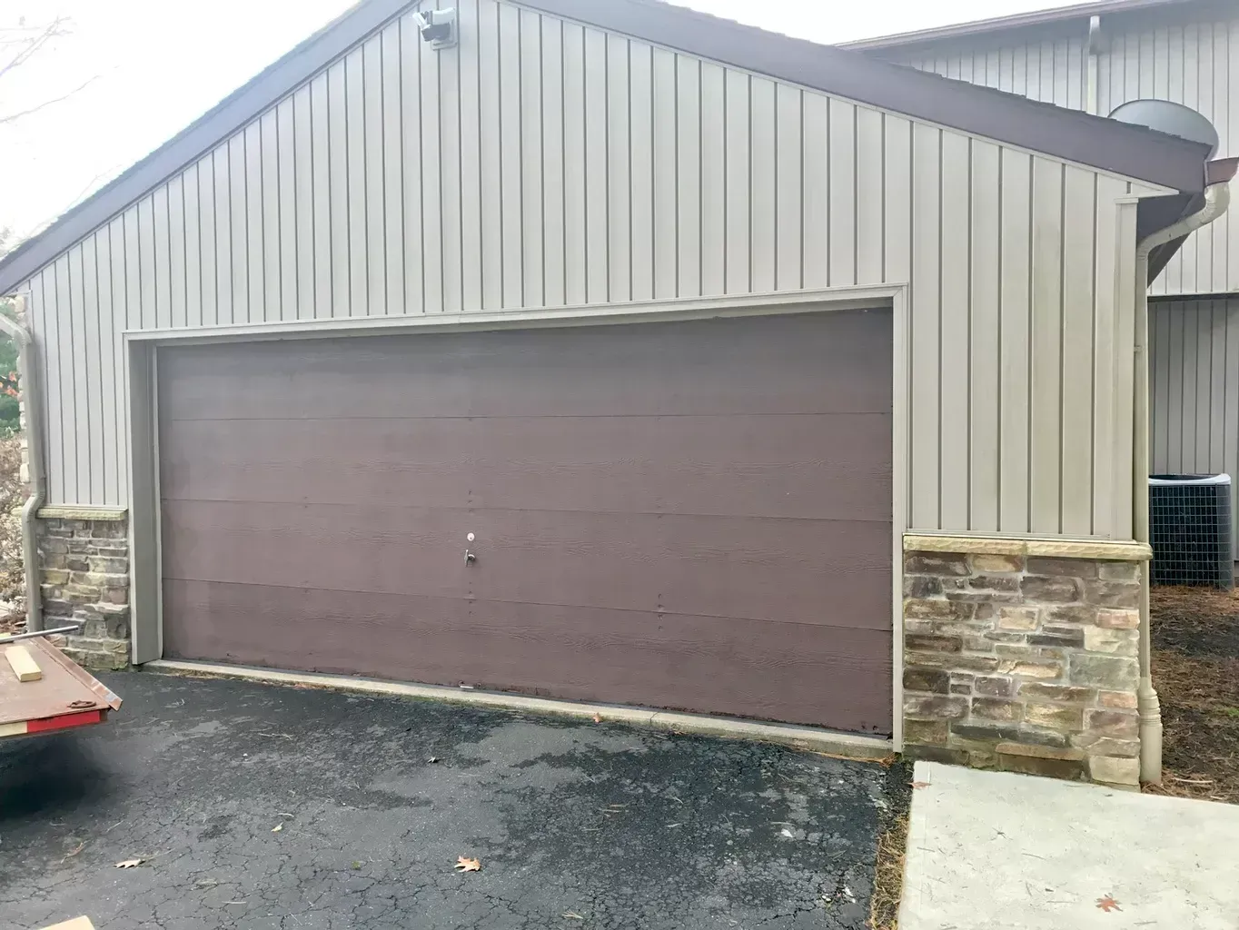 A garage with a brown garage door is next to a house.