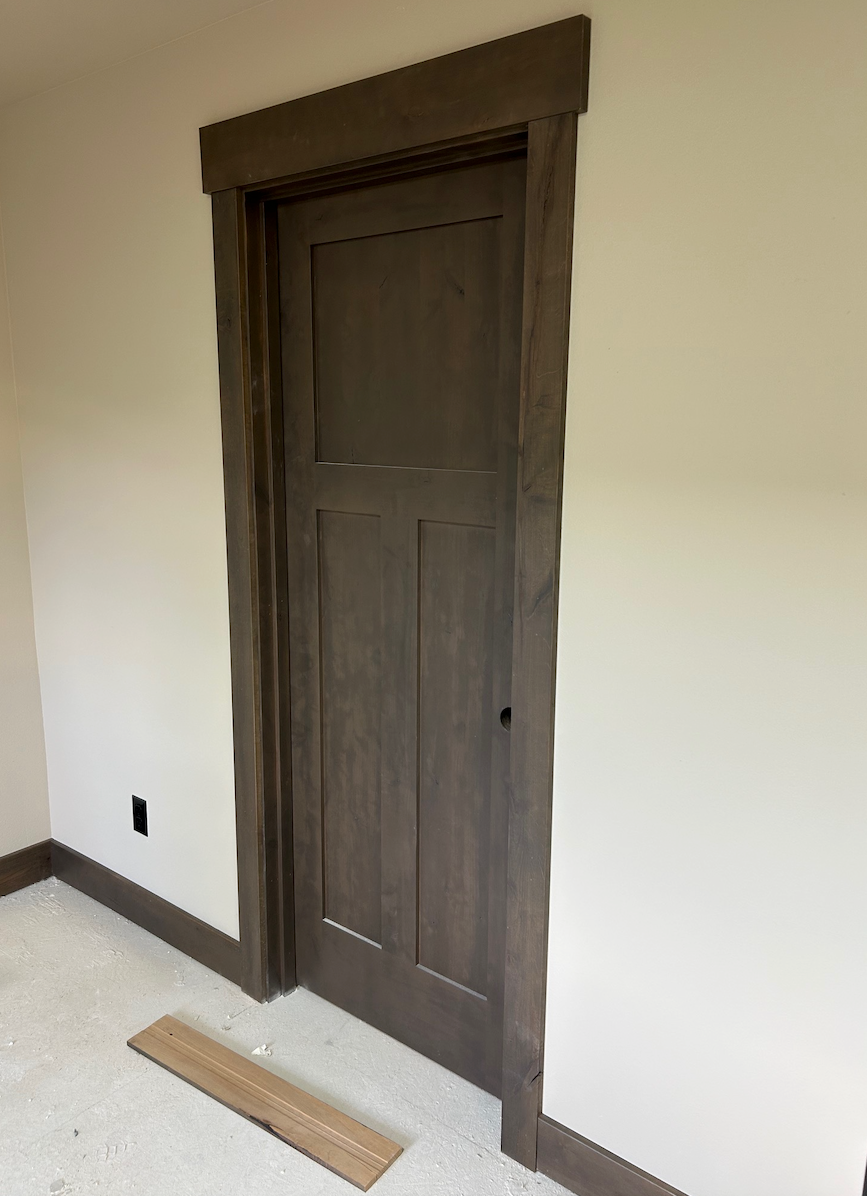 A wooden door is sitting in a room next to a wooden floor.