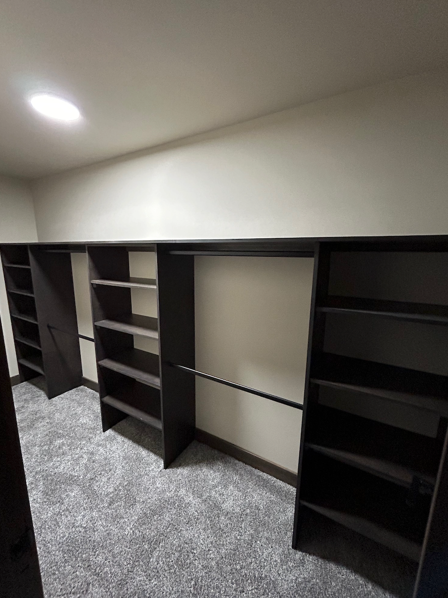 A walk in closet with lots of shelves and a light on the ceiling.