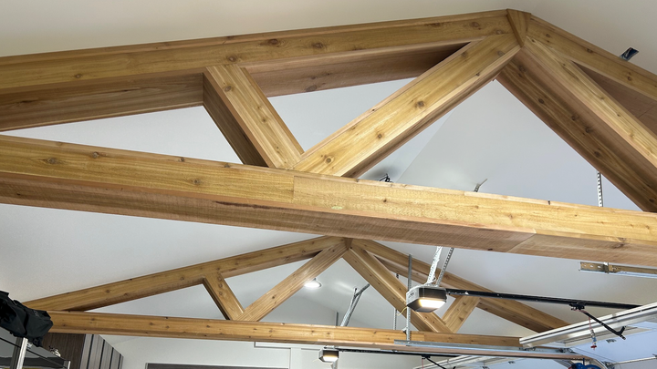 The ceiling of a garage with wooden beams and a ceiling fan.