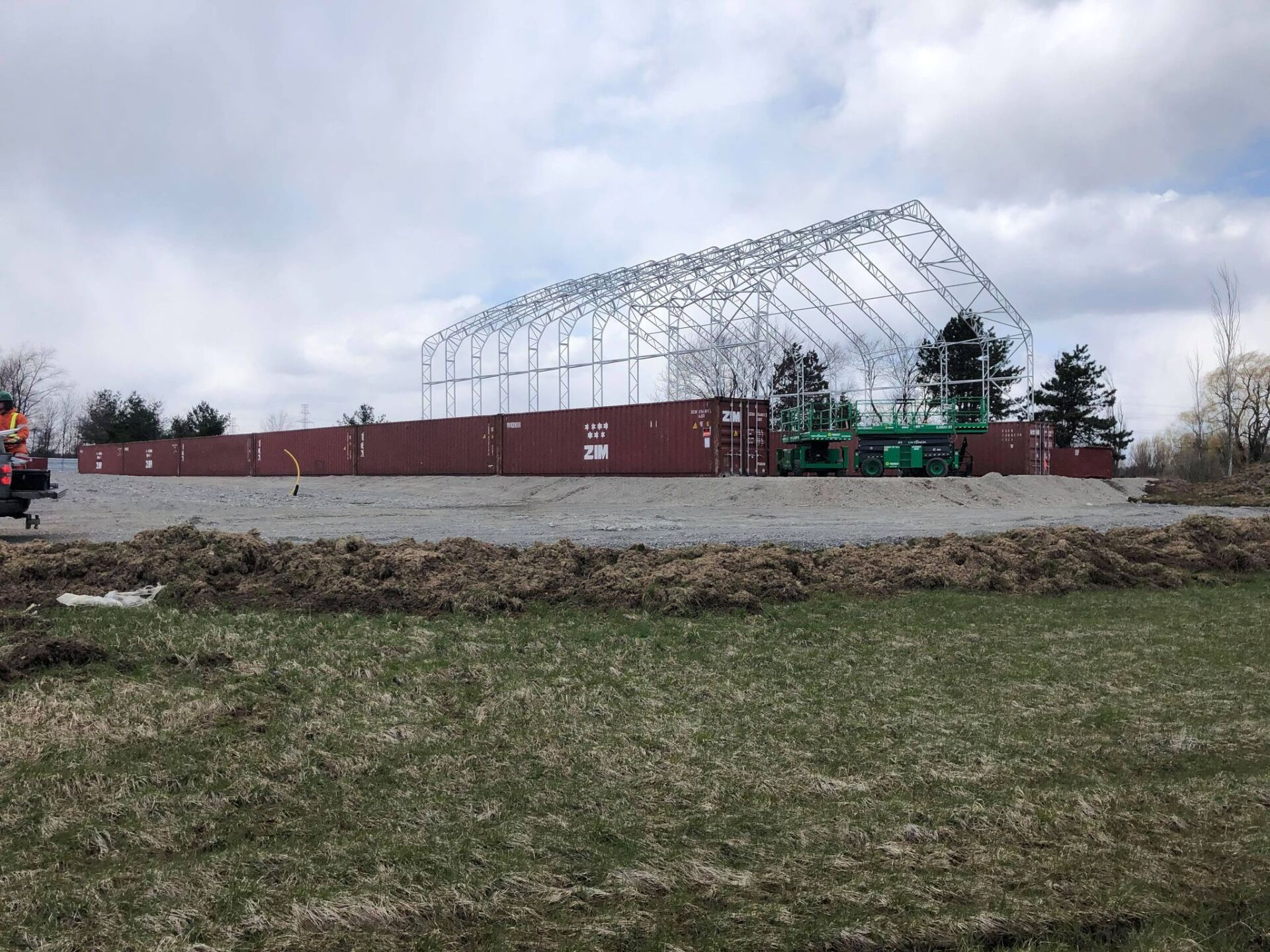 A large building is being built in the middle of a field on containers