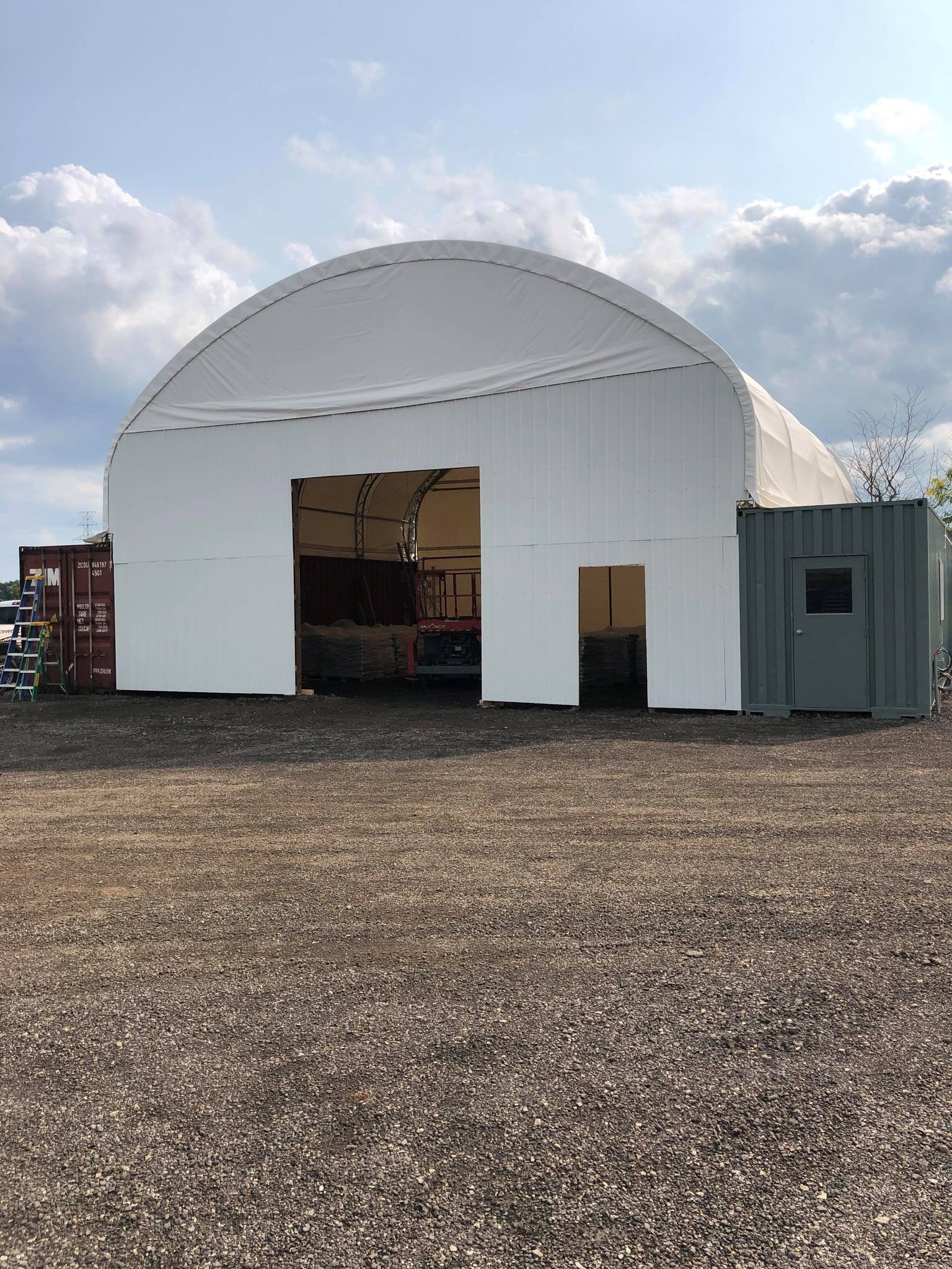 A large white building is sitting in the middle of a gravel field.