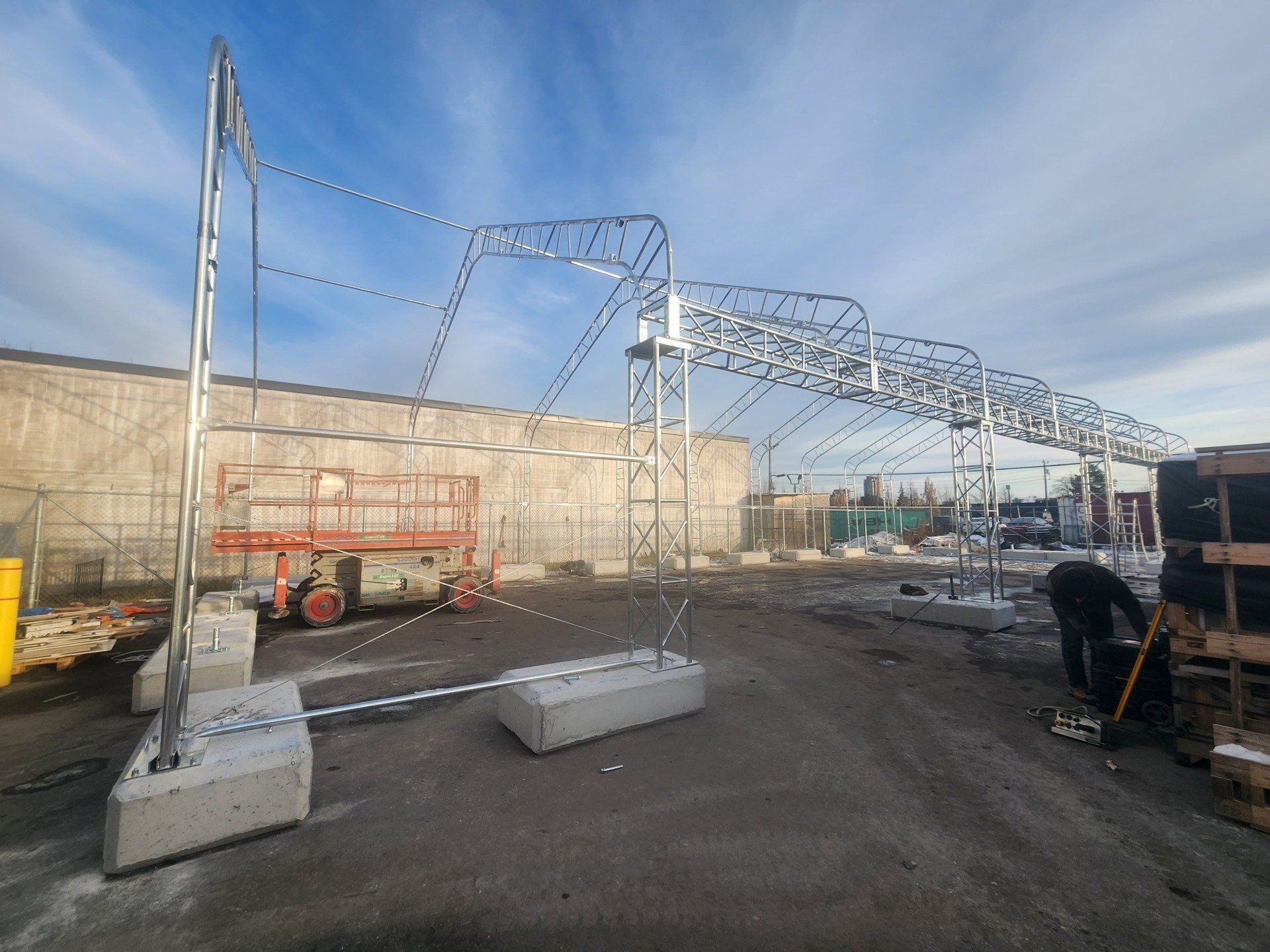 A large metal structure is being built in a parking lot