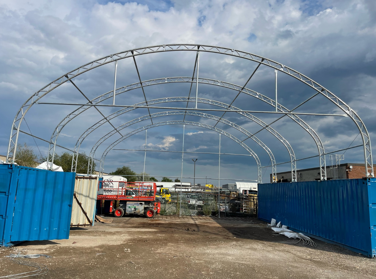 A large metal structure is being built in a parking lot.