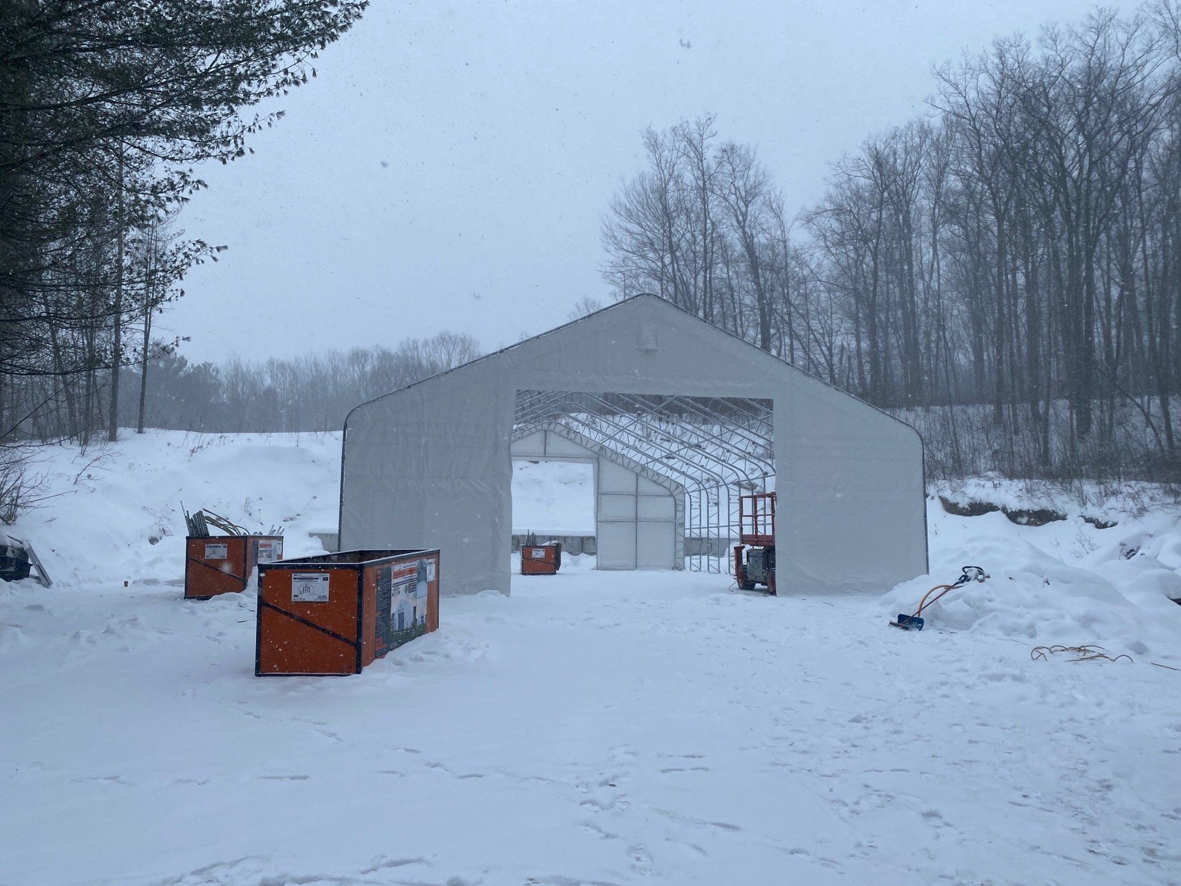 A large white tent is sitting in the middle of a snowy field.