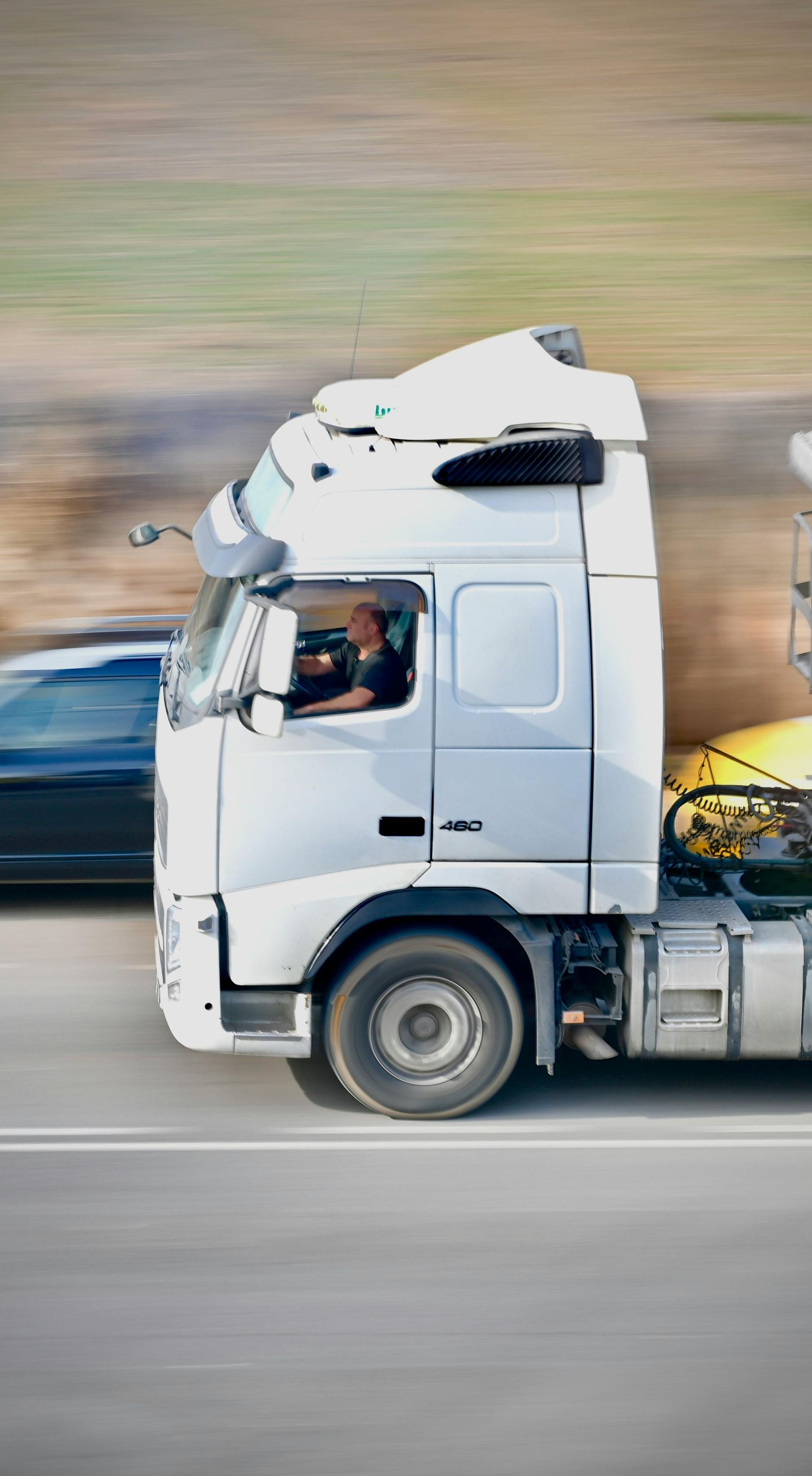 White semi-truck driving on a highway, side view with motion blur background