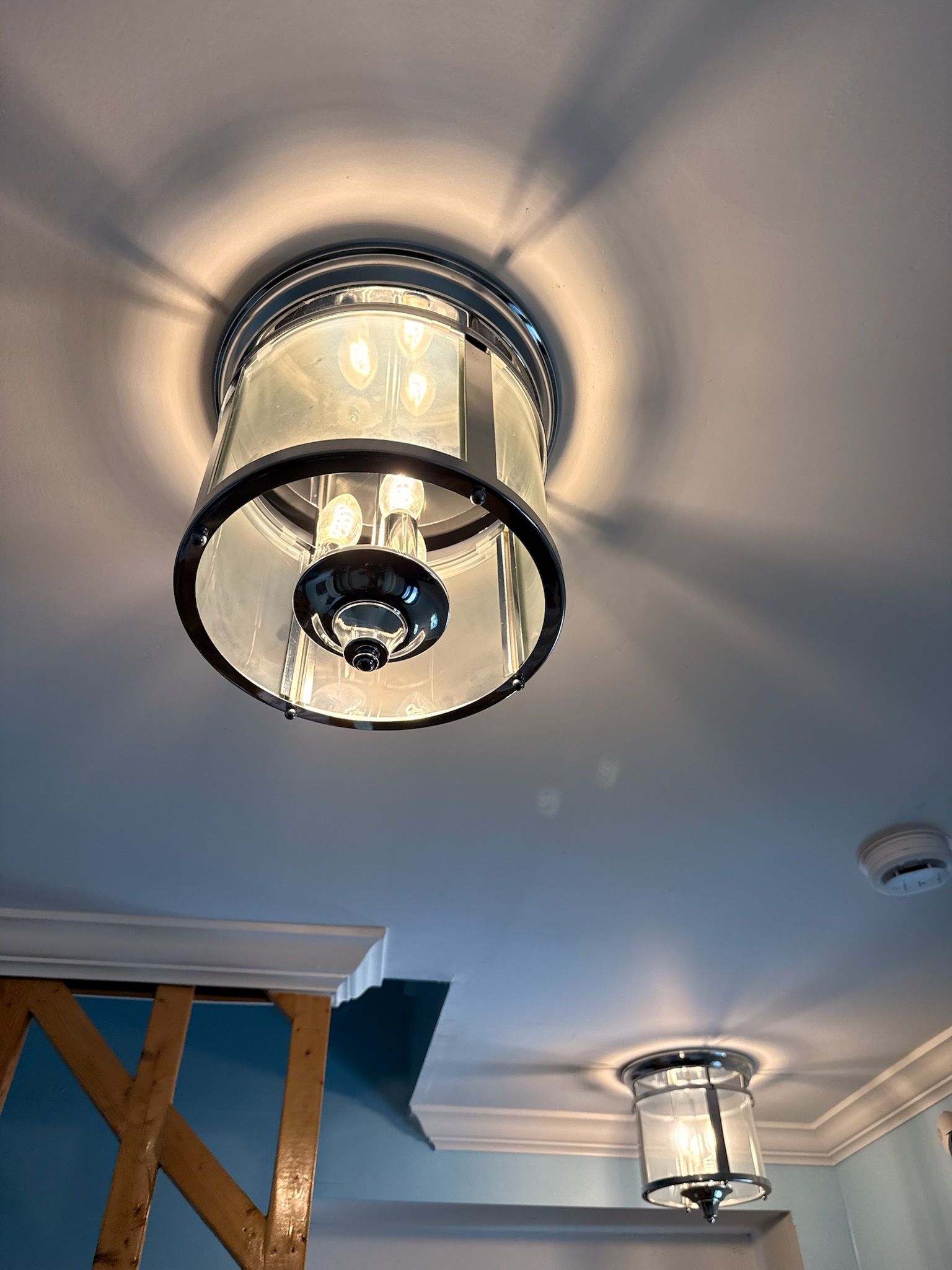 Ceiling with modern glass light fixtures in a room with light blue walls and white crown molding